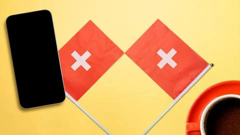 Flat lay composition with two small Swiss flags, a smartphone with a blank .. 写真素材