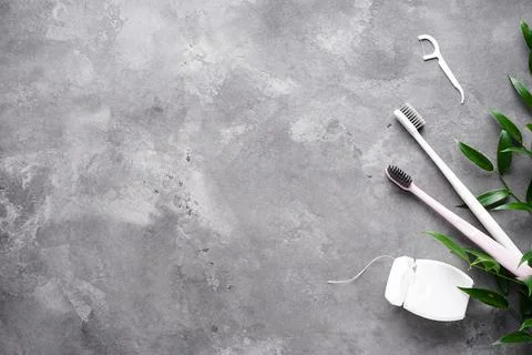 Flat lay composition of two toothbrushes, a toothpick and dental floss on a g Foto stock