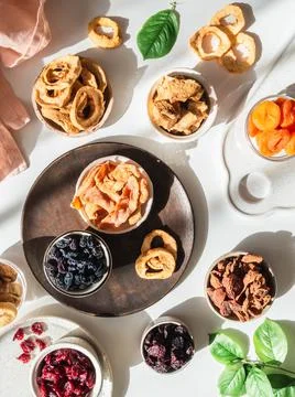 Flat lay composition of various dried fruits and berries in bowls on white ba Stock Photos