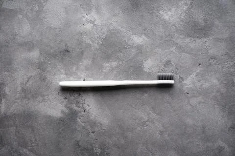 Flat lay composition of a white toothbrush with black bristles on a gray back Stock Photos