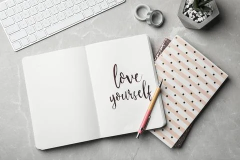 Flat lay composition with words LOVE YOURSELF written in notebook on grey tab Foto stock