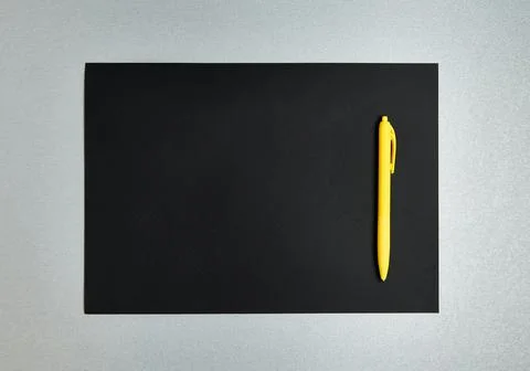 Flat lay composition with yellow pen on a black designer paper on a gray back Stock Photos