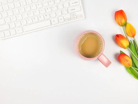 Flat lay of computer keyboard, pink cup of coffee and tulips on white backgro Stock Photos