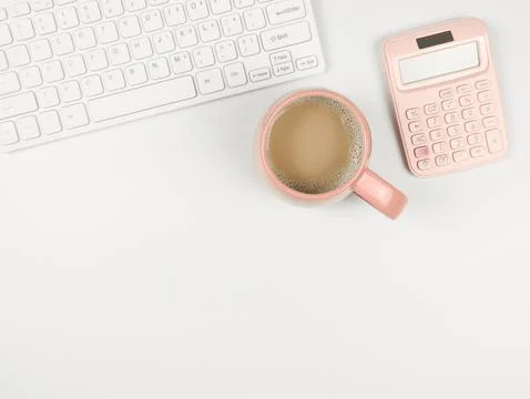 Flat lay of computer keyboard, pink cup of coffee and pink calcularor  on whi Stock Photos
