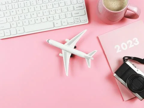 Flat lay of computer keyboard, pink cup of coffee, airplane model, 2023 dia.. Stock Photos