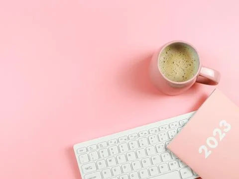 Flat lay of computer keyboard, pink coffee cup  pink diary or planner  2023.. Stock Photos