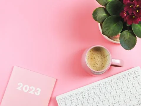 Flat lay of computer keyboard, pink coffee cup  pink diary 2023 and African.. Stock Photos