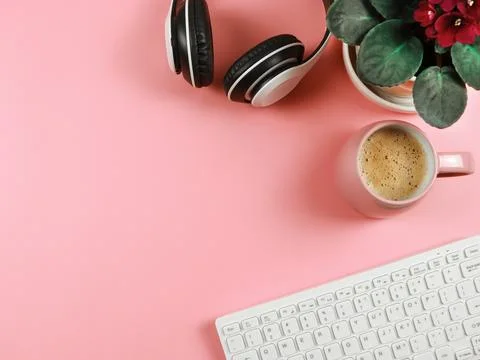 Flat lay of computer keyboard, pink coffee cup, headphones  and African vio.. Stock Photos