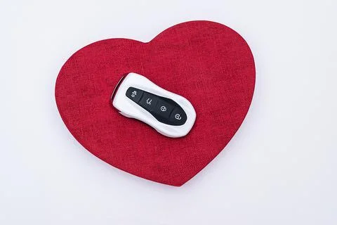 Flat lay concept and gift idea. Smart car key on a red embossed heart in the Stock Photos