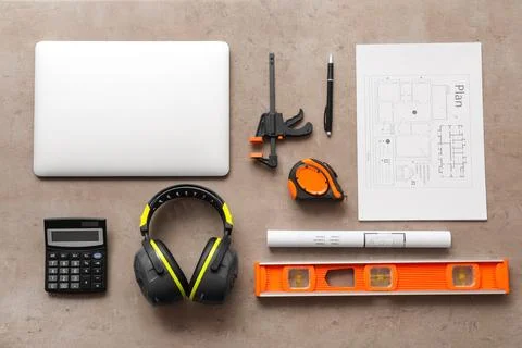 Flat lay of construction tools, safety earmuffs, and architectural plans on a Stock Photos