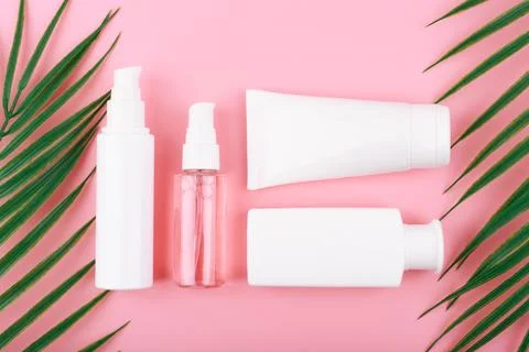 Flat lay with cosmetic set on pink background with palm leaves Stock Photos