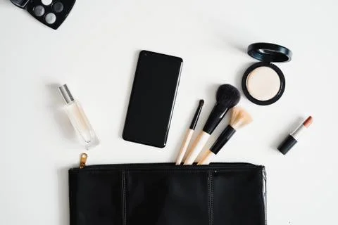 Flat lay of cosmetics, make up tools, clutch bag and mobile phone. Stock Photos