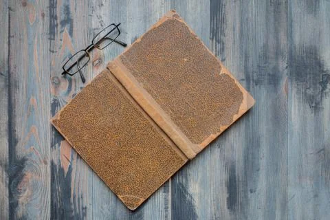 Flat lay of covered ancient book and glasses on vintage hoary background. Cop Stock Photos
