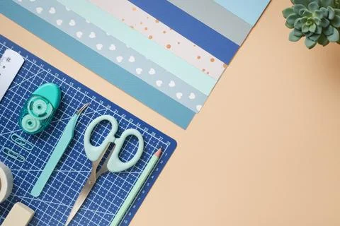Flat lay of craft tools. Scissors, tweezers, and cutting mat on beige backgro Stock Photos