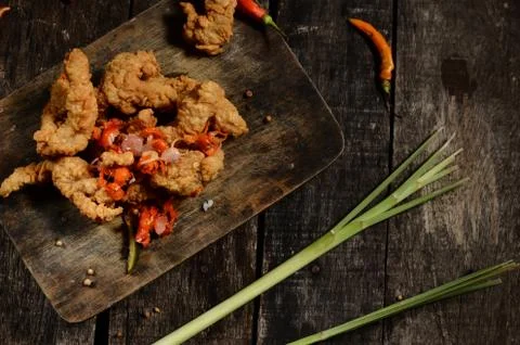 Flat lay crispy fried chicken pieces and Balinese sambal matah on a wooden ta Foto stock