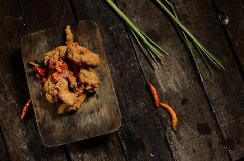 Flat lay crispy fried chicken pieces and Balinese sambal matah on a wooden ta Stock Photos