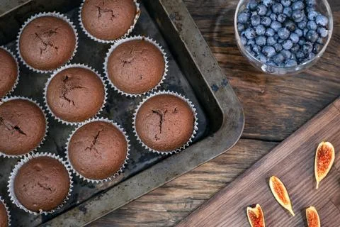 Flat lay cupcakes in bakeware, figs and berries on wooden table. Homemade muf Stock-Fotos