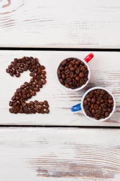 Flat lay cups with coffee beans and number two. Stock Photos