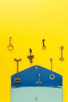 Flat lay of cute bag open out with a lot of old keys on colorful background w Stock Photos
