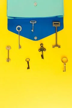 Flat lay of cute bag open out with a lot of old keys on colorful background w Stock Photos