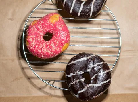 Flat lay of delicious doughnuts on grid stand on eco paper background Stock Photos