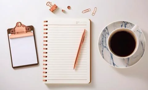 Flat lay desk with notebook, clipboard, coffee cup and pen, rose gold accesso Stock Photos