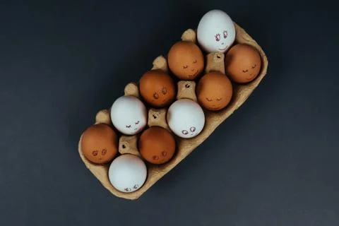 Flat lay of different Easter eggs with funny faces in carton box isolated on Stock Photos