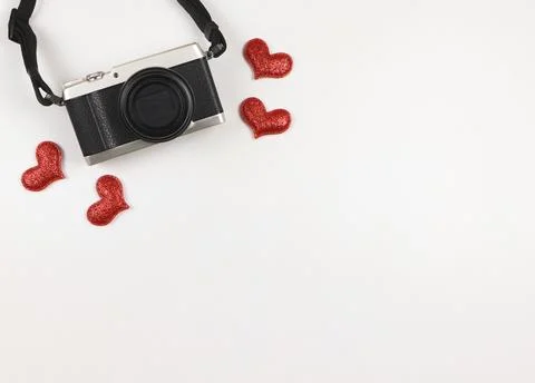 Flat lay of digital camera with red glitter hearts on white background with.. Stock Photos