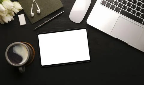 Flat lay digital tablet, laptop, coffee cup and supplies on black wooden tabl Stock Photos