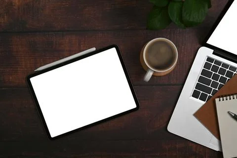Flat lay digital tablet, laptop, coffee cup, notebook and potted plant on wooden Stock Photos