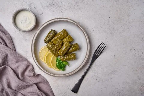 Flat lay dolma, stuffed grape leaves with rice and meat in light plate with with Stock Photos