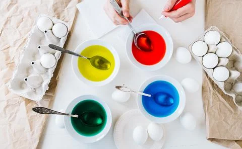 Flat lay. Dyeing Easter eggs with liquid food coloring. Different colors in d Stock Photos