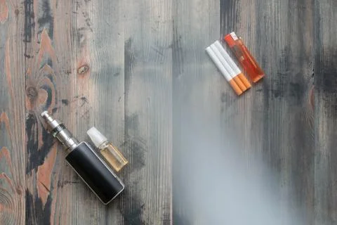 Flat lay of e-cigarette and e-liquid versus tobacco cigarettes with lighter o Stock Photos