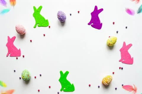 Flat lay easter background colored bunnies and eggs on white background with Stock Photos