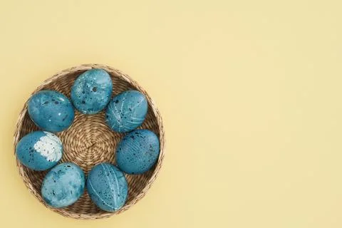 Flat lay with Easter eggs in a basket on a trendy yellow background. Space for Stock Photos