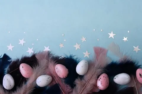 Flat lay easter eggs with dark blue, pink feather on mint color backdrop, sil Stock Photos