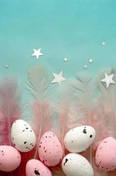 Flat lay easter eggs with diffrent pink feathers on blue color backdrop, silver Foto stock