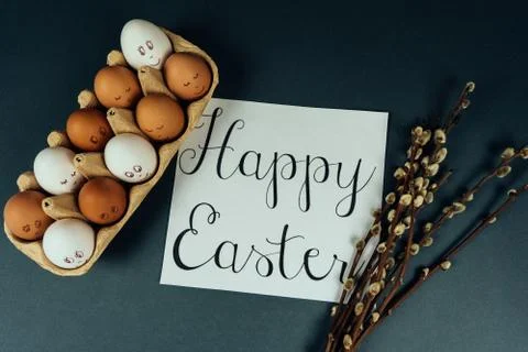Flat lay Easter eggs with painted faces in carton box and willow catkins Stock Photos