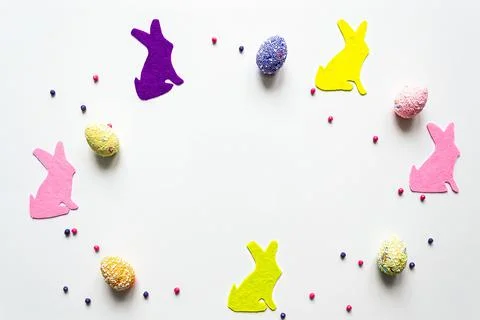 Flat lay easter holiday creative background with eggs and colored bunnies Stock Photos