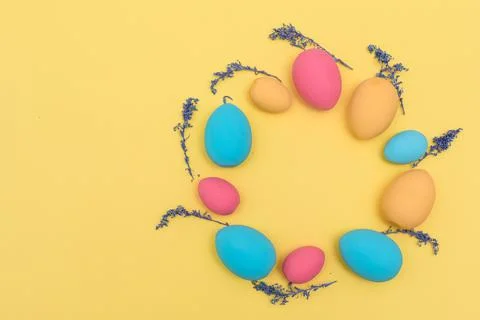 Flat lay Easter pastel colored eggs shaped on wreath on yellow background Stock Photos