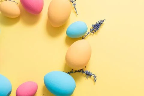 Flat lay Easter pastel colored eggs shaped on wreath on yellow background Stock Photos
