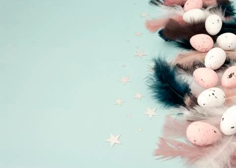 Flat lay easter quail eggs with dark blue, pink feather on mint color backdro Stock Photos