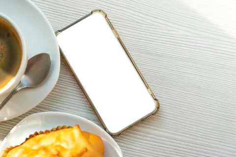 Flat lay, empty smartphone on table with hot coffee and snack or bakery in mo 스톡 사진