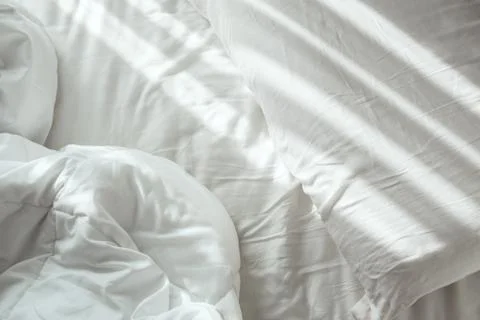 Flat lay of empty white sheets bed with bright sunlight on a pillow Stock Photos