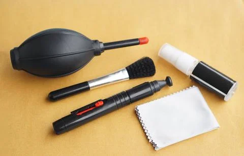 Flat lay of essential camera cleaning tools including air blower, soft brush, le Stock Photos