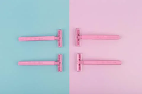 Flat lay with four pink plastic razors on pink and blue background Stock Photos