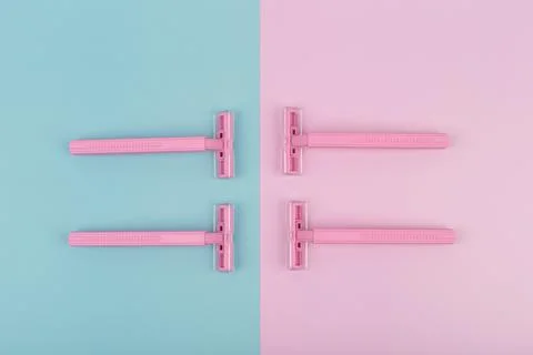 Flat lay with four pink plastic razors on pink and blue background Stock Photos