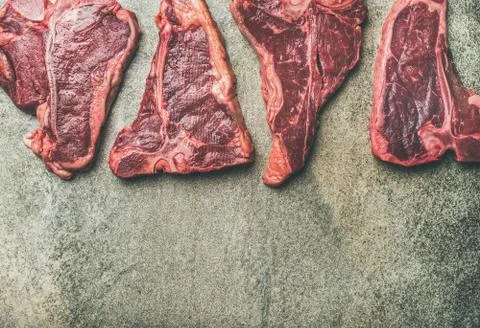 Flat-lay of fresh raw beef meat steaks over concrete background Stock Photos