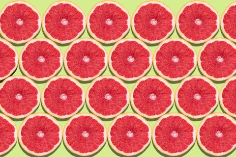 Flat lay fruit pattern of fresh grapefruit slices on green background. Stock Photos