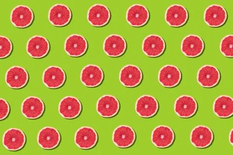 Flat lay fruit pattern of fresh grapefruit slices on green background. Stock Photos